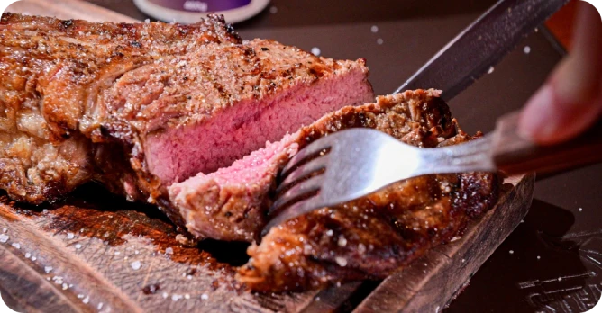 Corte bovino grelhado ao ponto sendo fatiado em tábua de madeira na churrascaria Steak Ranch