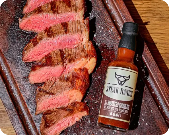 Fraldinha fatiada ao ponto em tábua ao lado do molho de pimenta Habanero Chocolate Steak Ranch